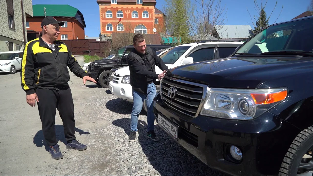 Воронько Дмитрий Николаевич осматривает полученный Toyota Land Cruiser 200 рядом с ведущим Garage 54